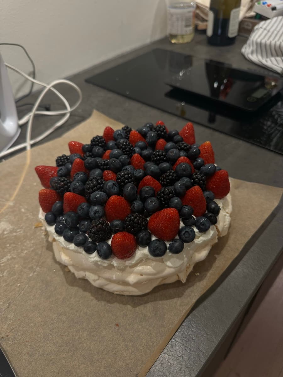 Homemade pavlova piled with strawberries, blueberries and blackberries